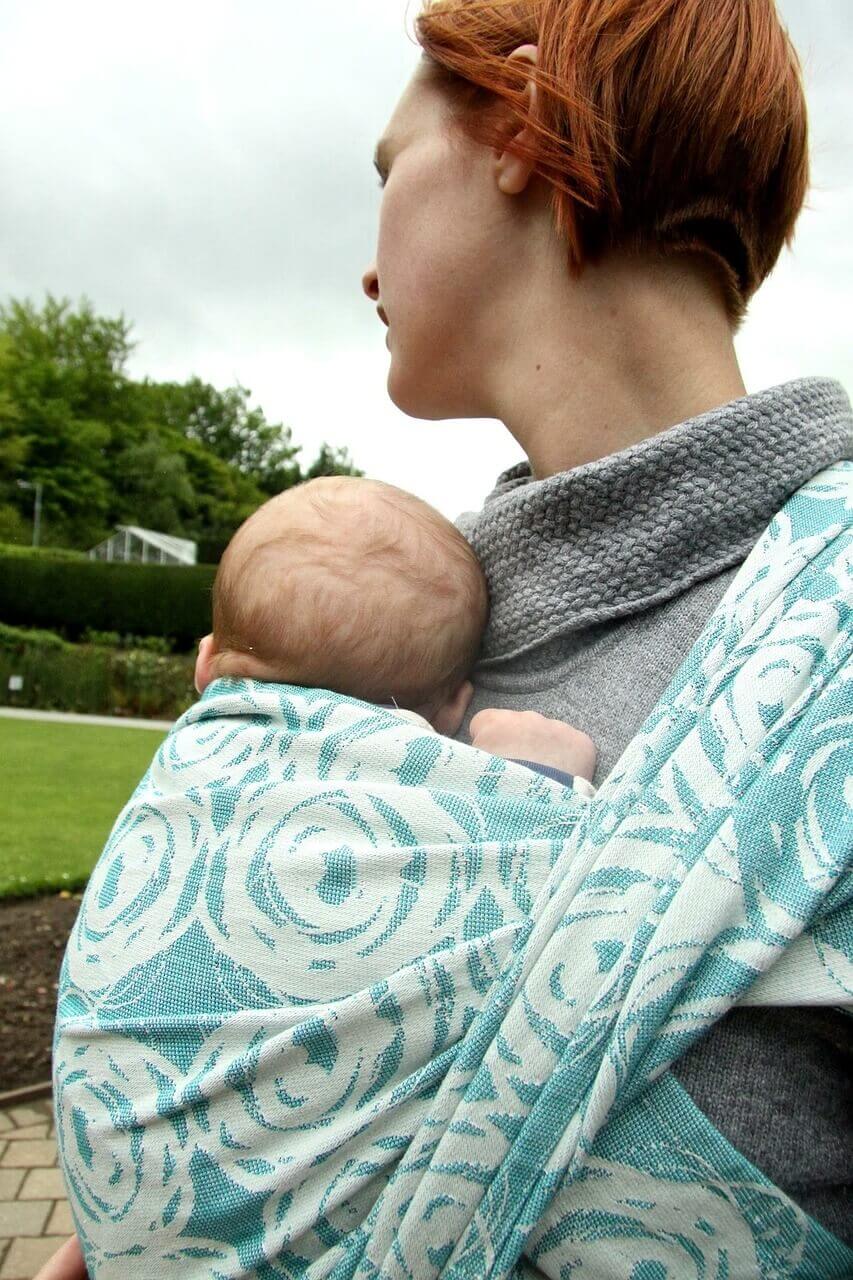 Mãe com bebê em sling estampado nas cores azul claro e branco