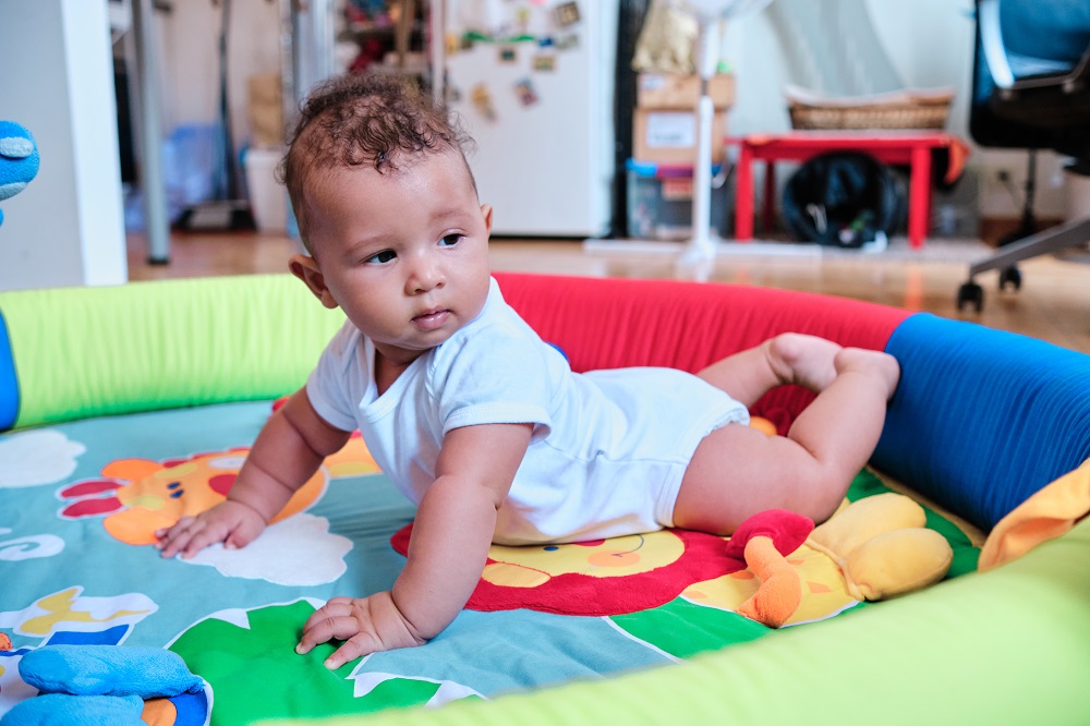Bebê fazendo tummy time em tapete colorido Bebê fazendo tummy time em tapete colorido